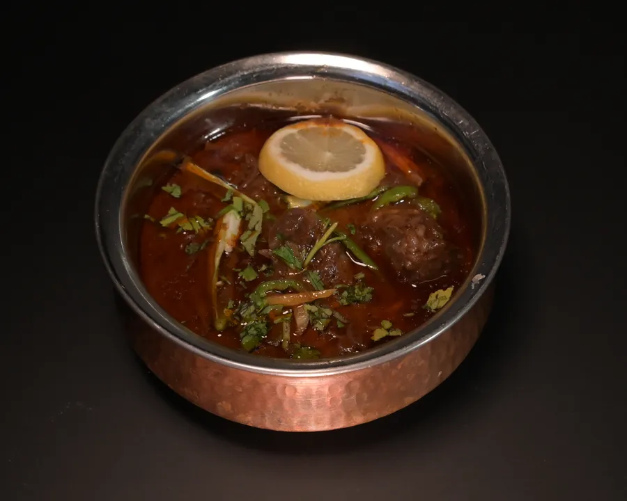 Beef nihari in a rich spiced gravy, served in a hammered copper handi with lemon