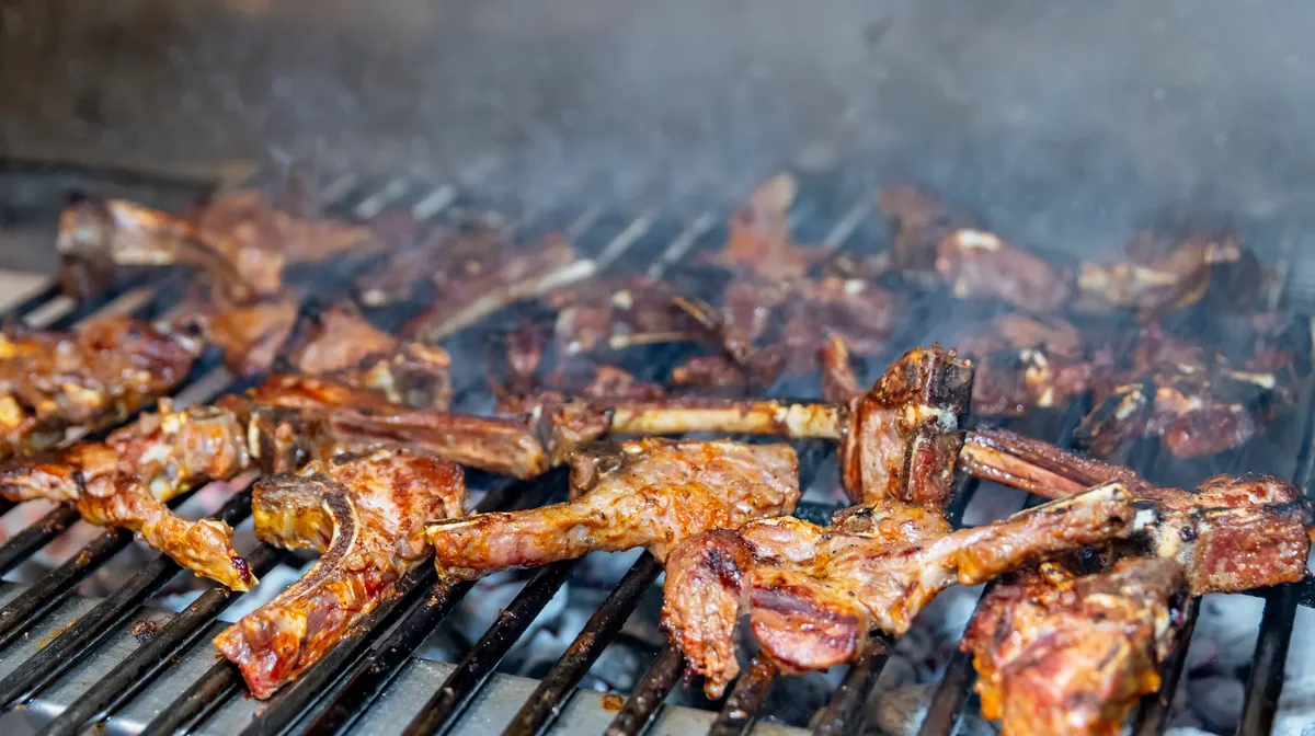 Marinated lamb chops cooking over the charcoal grill, smoke rising