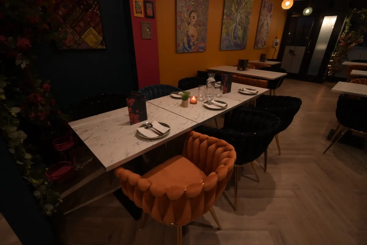 The dining room at 47: marble tables laid for dinner, velvet chairs and hand-painted murals on the walls
